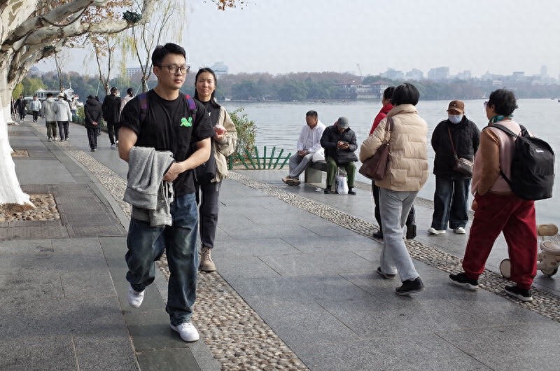 冬日暖阳下的西湖奇景：短袖游客与即将到来的寒流形成鲜明对比