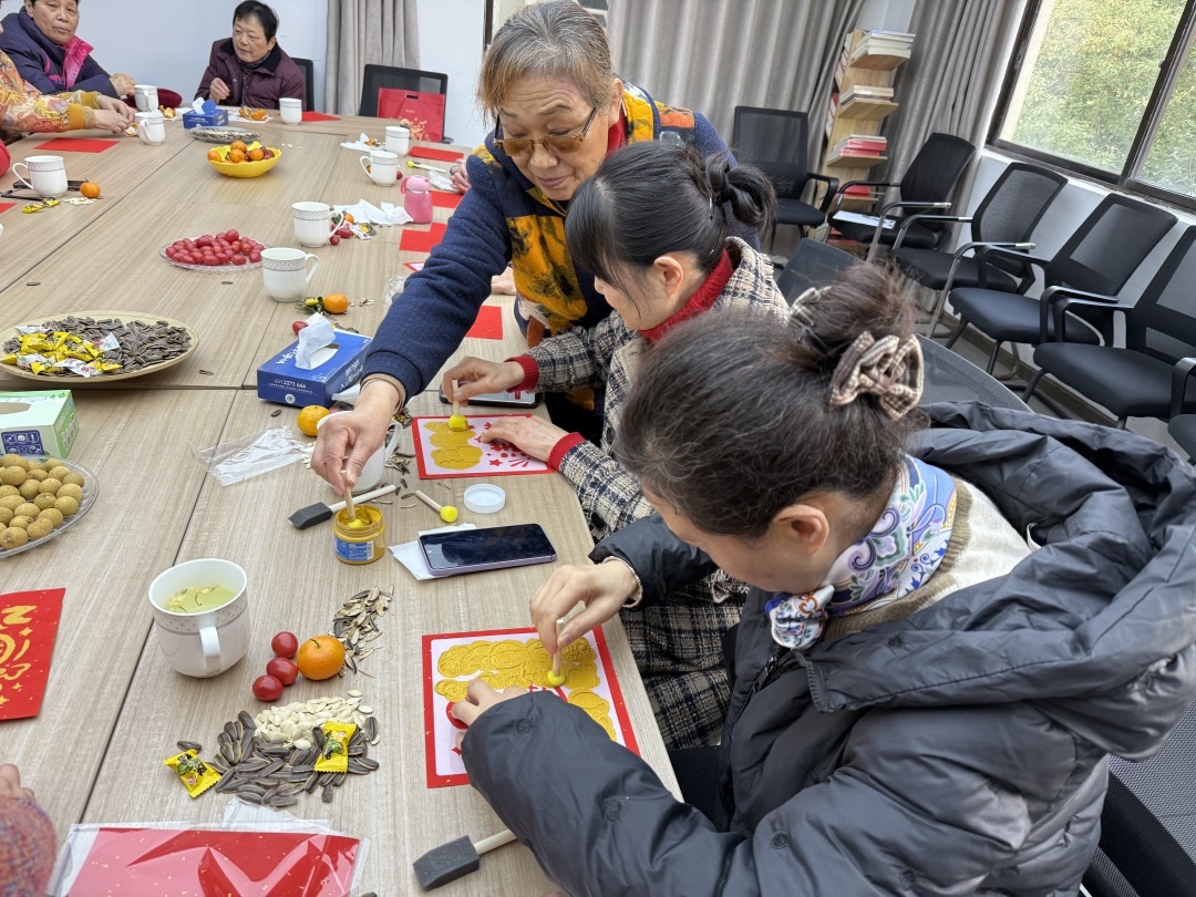 月河街道马军巷社区幸福邻里中心联合中宏保险举办茶话会，居民们亲手拓印福字，感受传统文化魅力